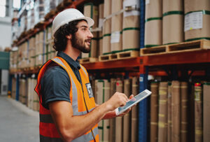 warehouse worker holding tablet while looking at inventory