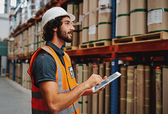 warehouse worker holding tablet while looking at inventory